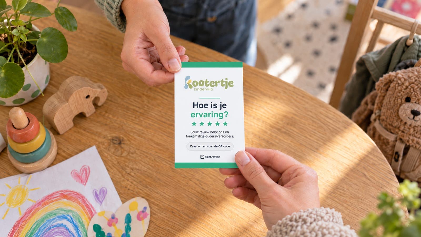 Een medewerker van Kindervilla Het Kootertje geeft een ouder het reviewkaartje met de vraag "Hoe is je ervaring?", aan een houten tafel met speelgoed en kindertekeningen