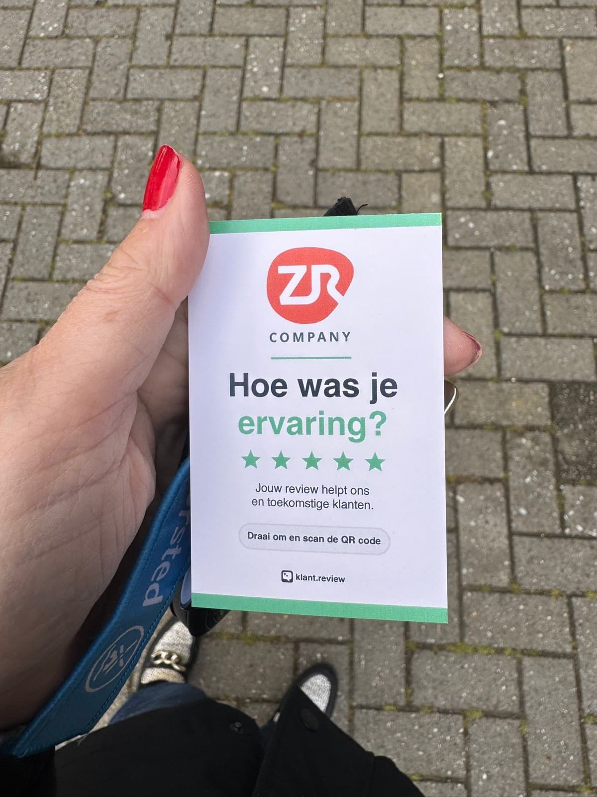 Voorbeeld-QR-review-kaartje van ZR Company in de hand, voorkant met logo, 'Hoe was je ervaring?' en vijf groene sterren