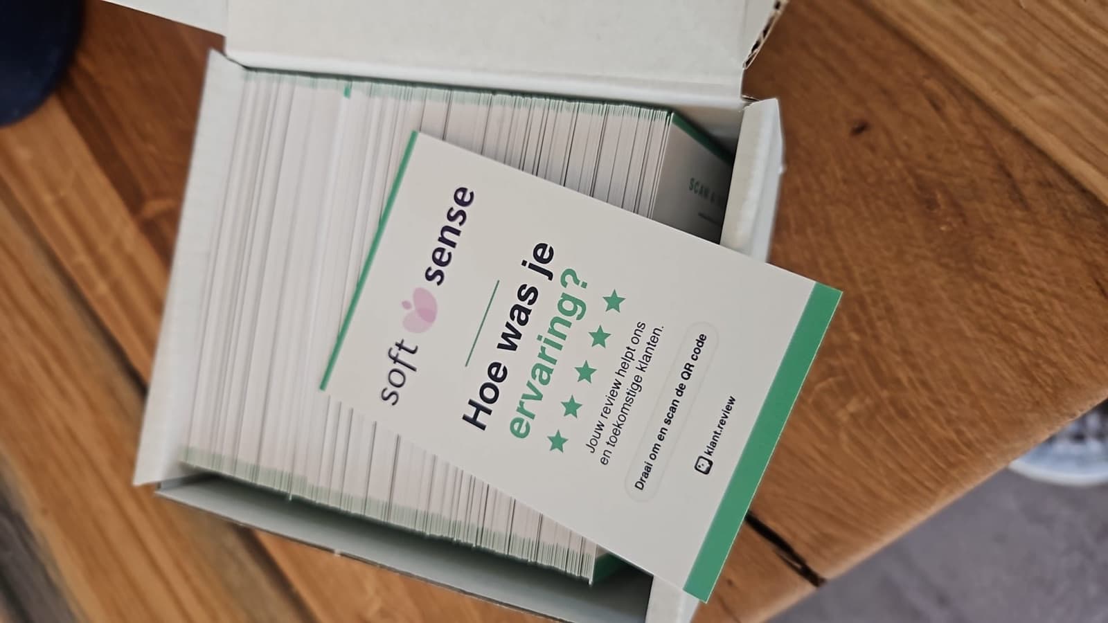 Doos met QR-review-kaartjes klaar voor verzending, bovenste kaartje toont 'Scan & Review' QR-zijde