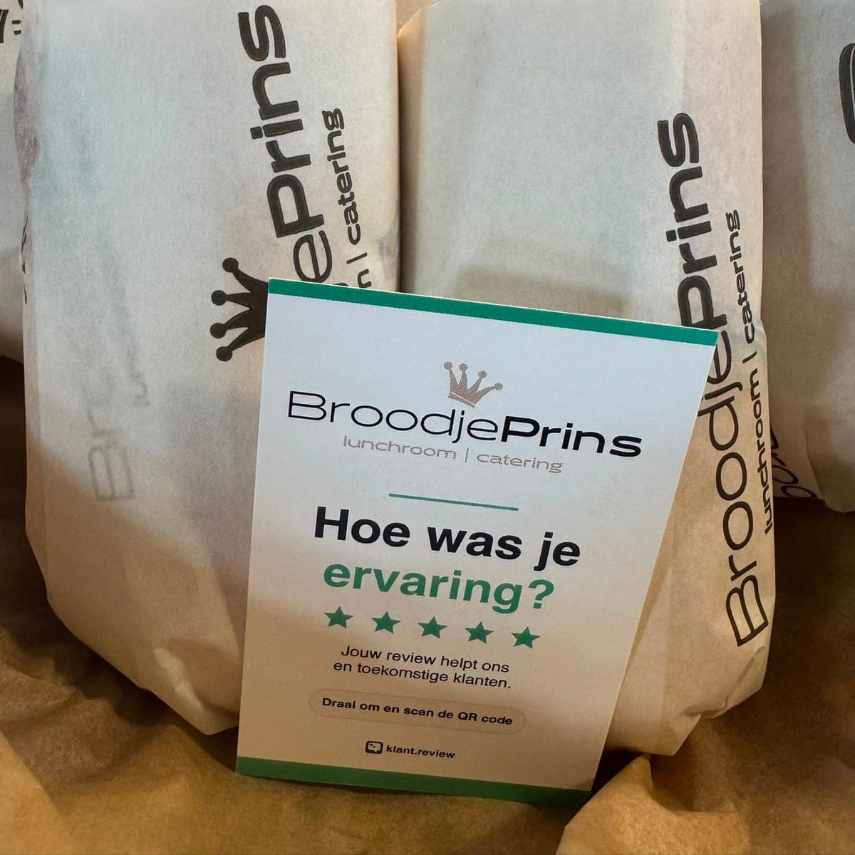 Reviewkaartje van lunchroom BroodjePrins met hun eigen logo, tussen ingepakte broodjes