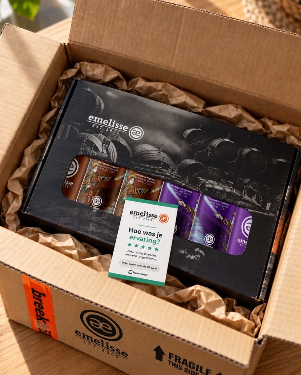 Open verzenddoos van Brouwerij Emelisse met een bierpakket, en bovenop het reviewkaartje met hun logo, de vraag 'Hoe was je ervaring?' en klant.review onderaan